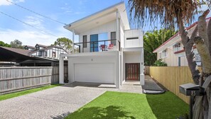 Une maison à deux étages, à l’extérieur blanc, avec un garage et une pelouse bien entretenue.