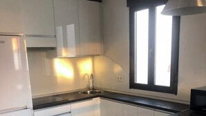 Une cuisine moderne avec des meubles blancs, un évier en acier inoxydable et un plan de travail noir.
