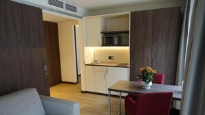 Espaço compacto com cozinha compacta, área de jantar com mesa e cadeiras, e um sofá.