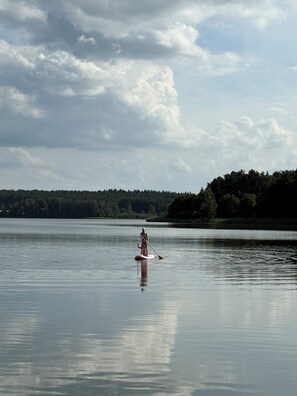Ein ruhiger See mit einer Person, die auf einem Stand-Up-Paddleboard fährt.