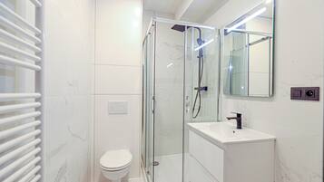 Een moderne badkamer met een douchekabinet van glas, een wit toilet en een wastafel met spiegel.