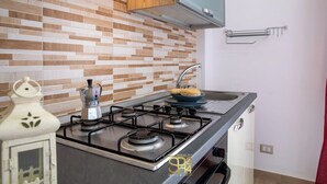 Una cocina moderna con estufa a gas, cafetera y un bol con pan en la encimera.