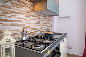 Eine moderne Küche mit einem Gasherd, einer Kaffeemaschine und einer Schüssel Brot auf der Arbeitsfläche.