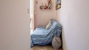 Un pasillo estrecho que da a un dormitorio con cama, un estante con adornos y un equipo de aire acondicionado en la pared.