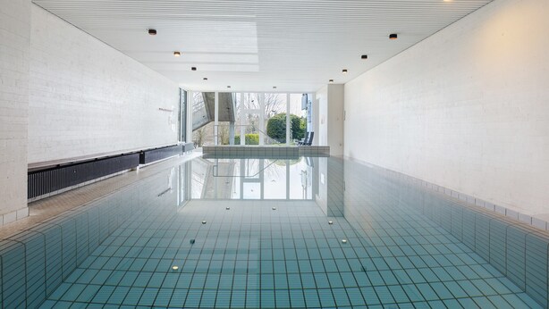 An indoor swimming pool with a tiled floor, white walls, and a ceiling with recessed lighting. - Apartment 'Schönblick' in a Quiet Location with Beautiful Views, Indoor Pool (Höchenschwand)