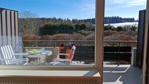 A balcony with a table and chairs, a view of a forested landscape, and a snow-covered field. - Apartment 'Schönblick' in a Quiet Location with Beautiful Views, Indoor Pool (Höchenschwand)