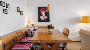A dining area with a wooden table, benches, a wall-mounted painting, and a lamp. - Apartment 'Schönblick' in a Quiet Location with Beautiful Views, Indoor Pool (Höchenschwand)