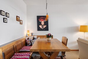 Un comedor con una mesa de madera, bancos, un cuadro colgado en la pared y una lámpara.