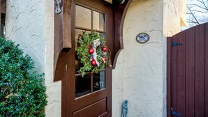 A wooden door with a glass panel, a wreath with red ornaments, and a sign on the wall. - Highland Ave (Norwalk)