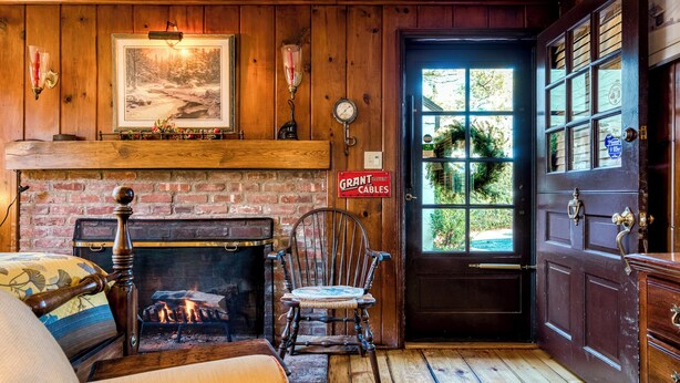 A cozy room with a fireplace, a wooden door, and a bench. - Highland Ave (Norwalk)