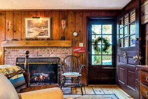 A cozy room with a fireplace, a wooden door, and a bench. - Highland Ave (Norwalk)