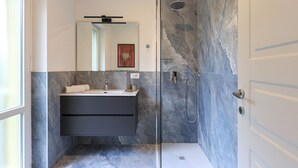 Un baño moderno con ducha envuelta en vidrio, tocador con lavabo y espejo.