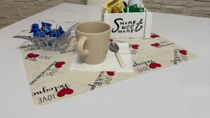 Una mesa con una taza color crema, una cuchara y una caja que contiene té Twinings Earl Grey y otros artículos.
