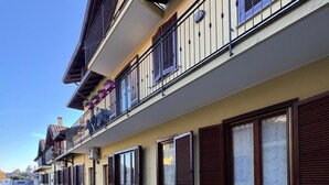 Un edificio de varios pisos con balcones, ventanas amplias y un camino de entrada de grava.