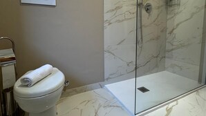 Un baño con cabina de ducha de vidrio, un inodoro y una toalla sobre él.