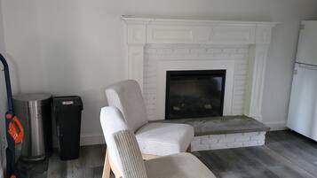Un salon avec une cheminée, un canapé, une poubelle et un aspirateur.