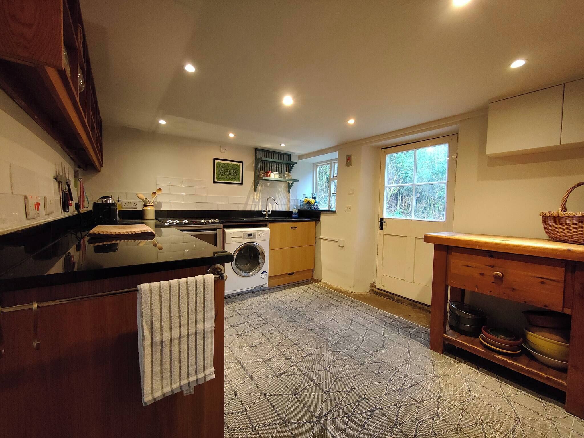 A kitchen with a washing machine, a countertop, and a window.