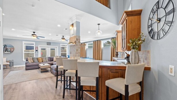 A spacious living area with a large sofa, a dining area with bar stools, and a kitchen with a wooden island. - Good Vibes: New Mgmt 2026, Relaxing Private Escape w/ Pool & Beach Service (Destin)