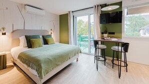 A bedroom with a bed, a table with two chairs, a TV, and a balcony with a view. - Neostelia (Annecy)