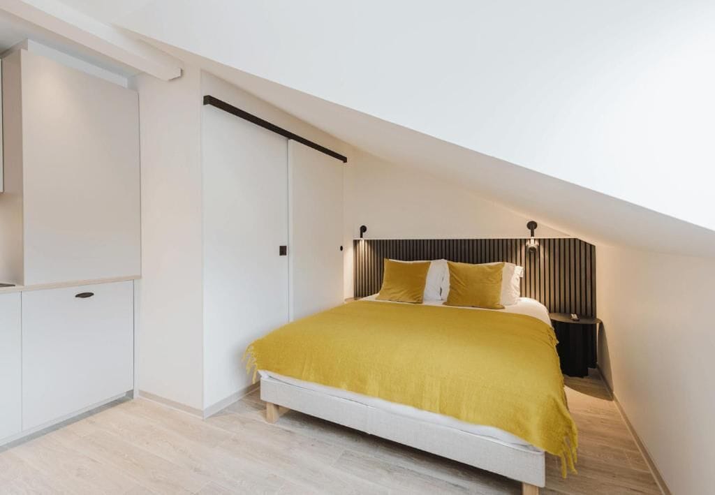A bedroom with a bed, a wardrobe, and a nightstand.