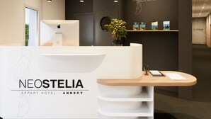 A reception desk with a modern design, a logo, and a wall with a logo and some books. - Neostelia (Annecy)