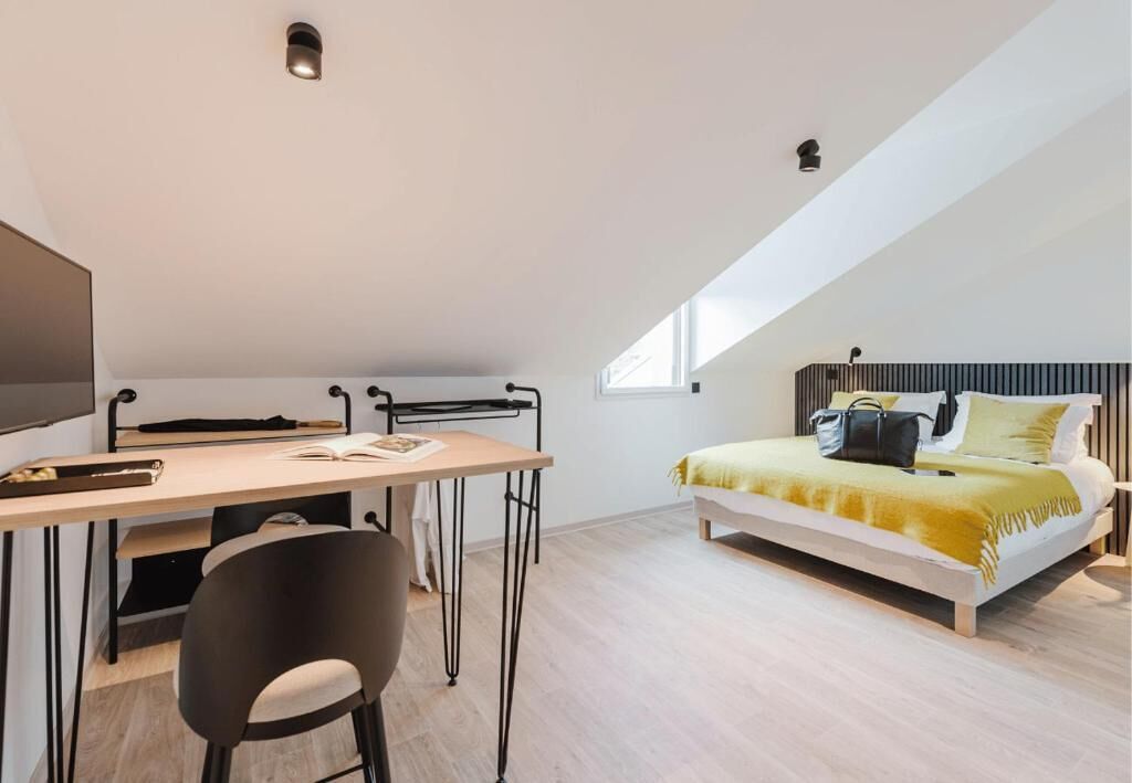 A bedroom with a bed, a desk, and a chair.