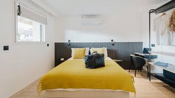 A modern bedroom with a bed, bedside table, chair, and a desk with a chair.