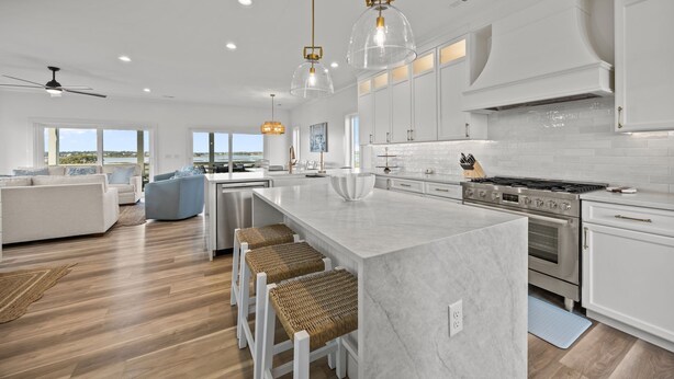 A modern kitchen with white cabinetry, a large island, stainless steel appliances, and pendant lighting. - The Jolly Gator #212 Resort Pool, Private Hot Tub, Elevator, Game Room (Surf City)