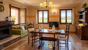 Un comedor con una mesa de madera, sillas, una araña y un televisor.