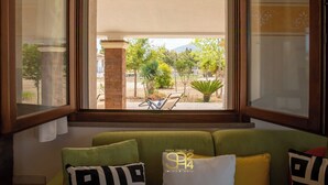 Habitación con vista a un patio, un sofá verde y una ventana con detalles decorativos.