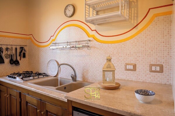 A kitchen with a gas stove, sink, and a decorative lantern on the countertop.