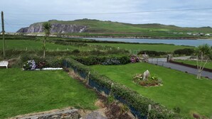 A rural landscape with a stone wall, a small pond, and a distant view of a hill with a cliff. - Ballyferriter Dingle Seaside Beautiful House (Ballyferriter)