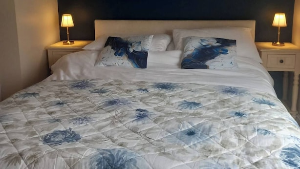 A bedroom with a bed, two bedside lamps, and a dark accent wall. - Ballyferriter Dingle Seaside Beautiful House (Ballyferriter)