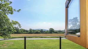 A room with a large window overlooking a grassy field and trees. - Daves Place (Much Wenlock)