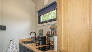 Una cocina compacta con un lavamanos, estufa y ventana sobre el lavamanos.