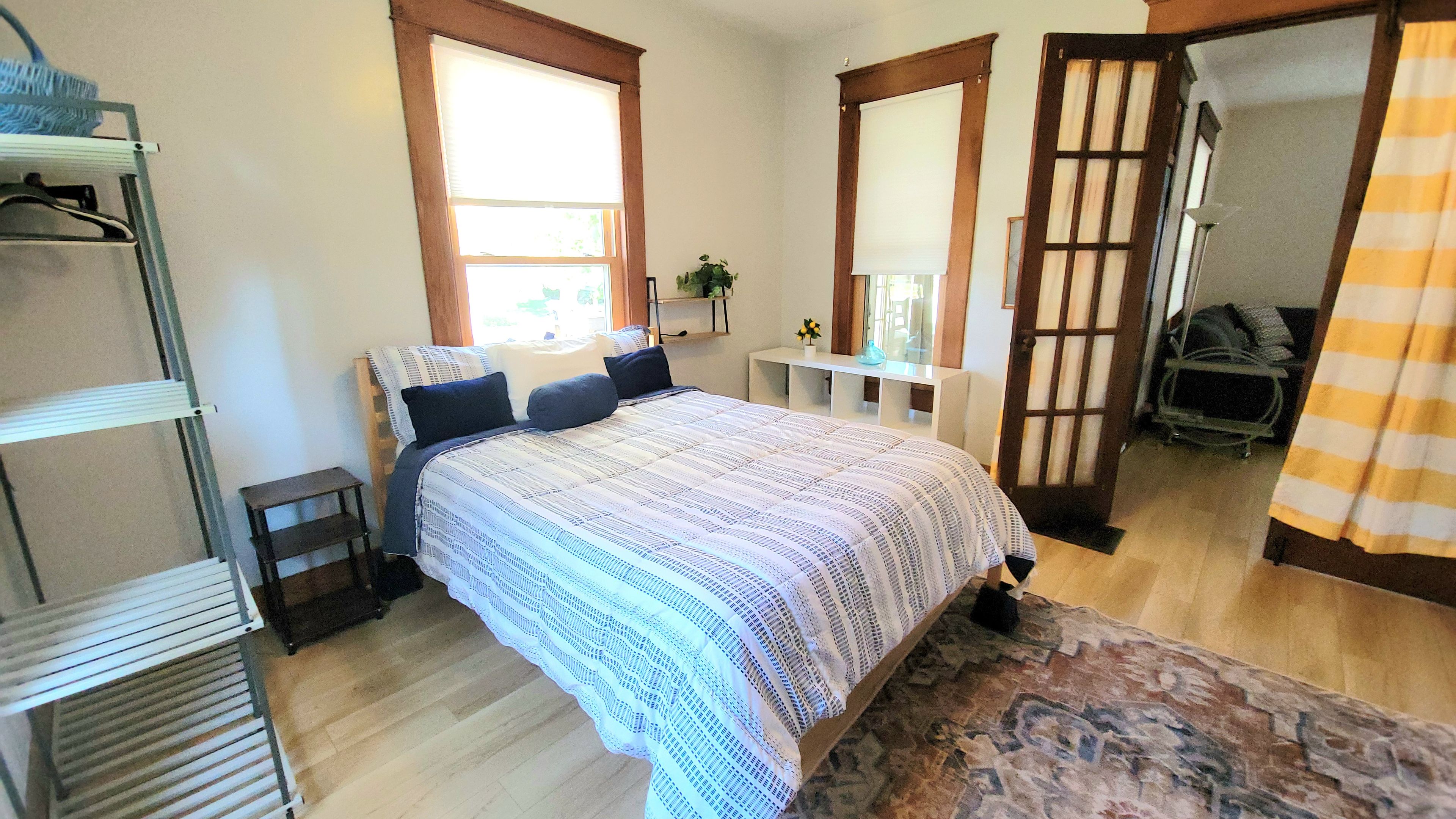 A bedroom with a bed, a desk, a chair, a wardrobe, and a bathroom.