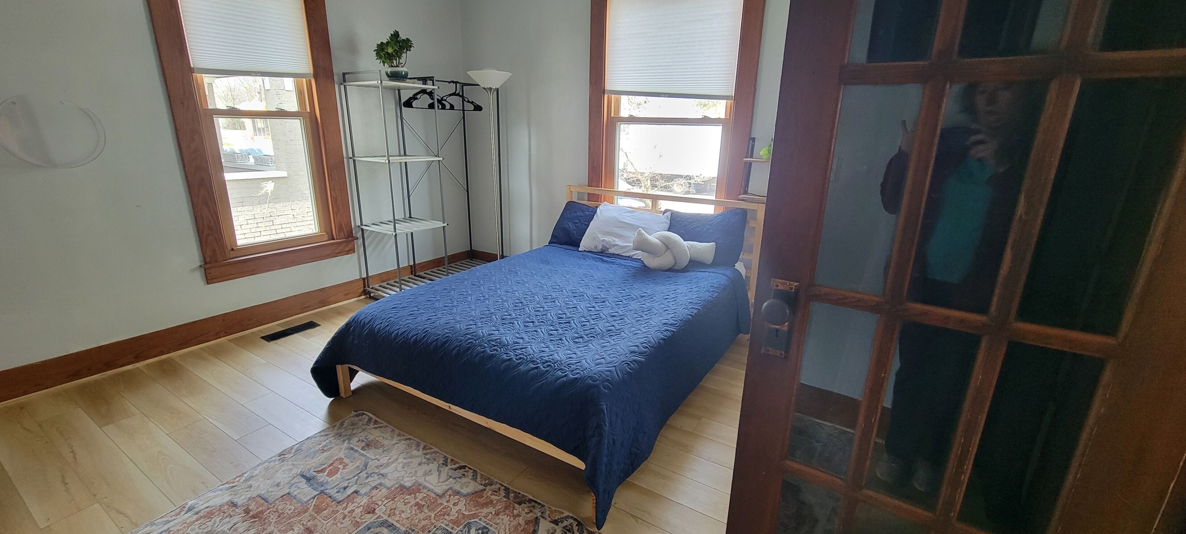 Een slaapkamer met een bed, vloerlamp, kast en raam.