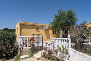 A yellow building with a white gate, a small window, and an air conditioning unit. - Casa Rosa Longterm Living and Workspace (Torrent)
