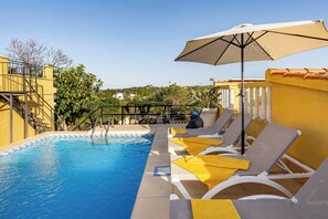 A pool area with lounge chairs and umbrellas, surrounded by yellow walls and a clear view of the landscape. - Casa Rosa Longterm Living and Workspace (Torrent)
