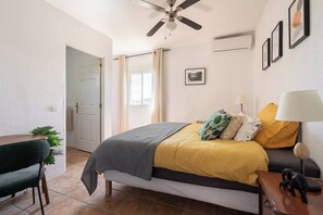 A bedroom with a bed, bedside table, lamp, and a ceiling fan. - Casa Rosa Longterm Living and Workspace (Torrent)