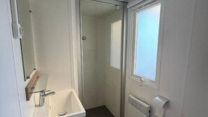 A modern bathroom with a glass shower enclosure, a white sink with a mirror, and a window providing natural light. - Bienvenue chez Jean - Your family oasis on the Rhone (Condrieu)