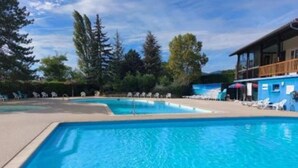 A rectangular swimming pool with clear blue water, surrounded by lounge chairs and a building with a balcony. - Bienvenue chez Jean - Your family oasis on the Rhone (Condrieu)