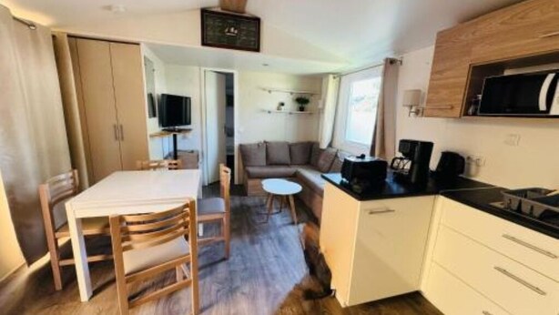 A compact living space with a dining area, kitchenette, and a seating area with a sofa and a small round table. - Bienvenue chez Jean - Your family oasis on the Rhone (Condrieu)