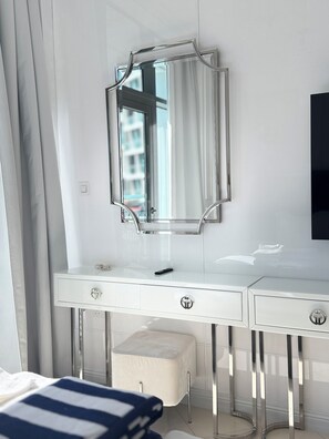 A modern bedroom with a white vanity, a mirror, and a bed with a striped bedspread. - Sea View, Stylish upgraded studio in Seven Palm (Dubai Emirate)