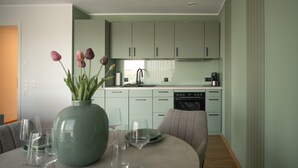 Cozinha moderna com armários verde-claros, área de jantar com mesa redonda e um vaso com flores.
