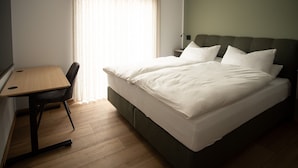 Quarto de hotel com cama, escrivaninha e cadeira.