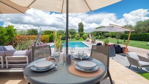 An outdoor dining area with a table set for two, surrounded by chairs and a large umbrella. - Villa Lavinia - Alghero (Alghero)