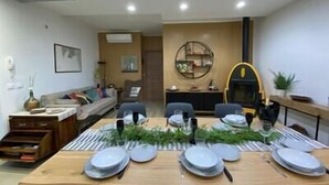 A dining area with a wooden table set for four, surrounded by chairs. There is a sofa and a small side table with a vase and a book in the background. - Villa Lavinia - Alghero (Alghero)