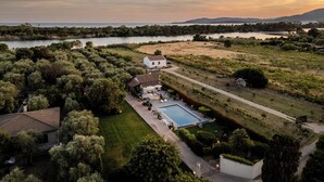 A large house with a swimming pool, surrounded by lush greenery and a lake. - Villa Lavinia - Alghero (Alghero)