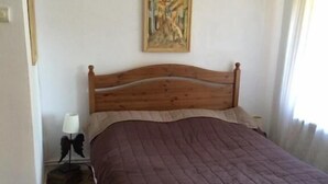 Ein Bett mit Holzkopfteil, ein Bild an der Wand und eine Lampe auf einem Nachttisch.